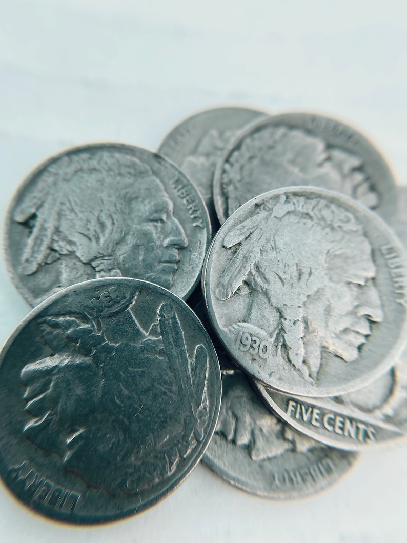 K&ouml;nnte beinhalten: Nahaufnahme eines Stapels silberfarbener US-F&uuml;nf-Cent-M&uuml;nzen mit dem Profil eines amerikanischen Indianers. Die M&uuml;nzen sind mit 1930 datiert und tragen die Inschriften "Liberty" und "Five Cents".