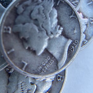 K&ouml;nnte beinhalten: Nahaufnahme eines Stapels Silberm&uuml;nzen mit der Aufschrift "In God We Trust" und dem Jahr "1939" auf der obersten M&uuml;nze.