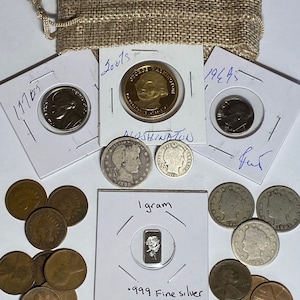May include: A collection of coins and a small silver bar on a white surface. The coins are mostly silver and copper in color. The silver bar is labeled "1 gram .999 Fine silver".