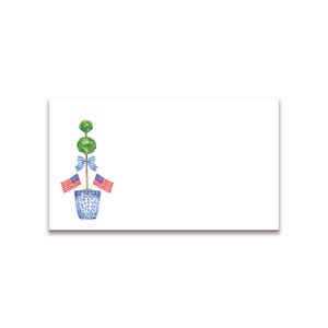 May include: A rectangular white card featuring a watercolor illustration on the left side. The design shows a double-ball green topiary in a blue and white patterned pot, decorated with a light blue striped bow and two small American flags.
