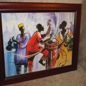 May include: A framed painting showing three figures in bright clothing, possibly musicians. The figures are painted in red, purple, and yellow, with a drum as a central element. The artwork is framed in a dark wood frame.