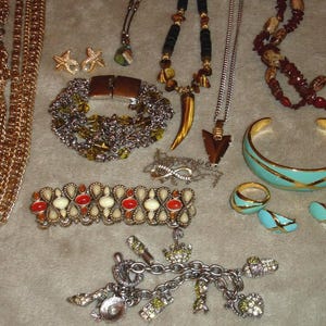 Könnte beinhalten: Eine Schmucksammlung mit Halsketten, Armbändern, Ohrringen, Ringen und einem Charm-Armband. Der Schmuck hat verschiedene Farben, darunter Gold, Silber, Türkis, Rot und Braun. Die Stücke haben verschiedene Designs, wie Sterne, geometrische Formen und Perlen.