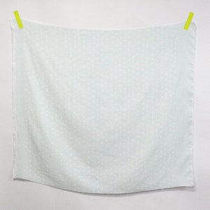 以下が含まれることがあります： 白い水玉模様の薄い青色の布。布は2つの黄色のクリップで吊り下げられています。