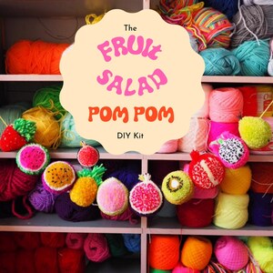Puede incluir: Estanter&iacute;a llena de hilos coloridos y decoraciones de frutas con pompones. El texto en la imagen dice "The Fruit Salad Pom Pom DIY Kit". Los pompones est&aacute;n dise&ntilde;ados para parecerse a varias frutas, incluyendo sand&iacute;a, kiwi y pi&ntilde;a.