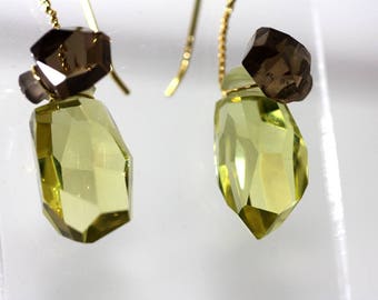 Puede incluir: Un par de pendientes de oro con un cristal facetado verde claro y un cristal facetado marrón en cada pendiente.