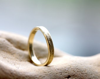 May include: A simple gold wedding band with a textured finish.
