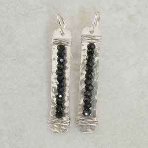 May include: A pair of silver earrings with black beads and hammered metal accents.