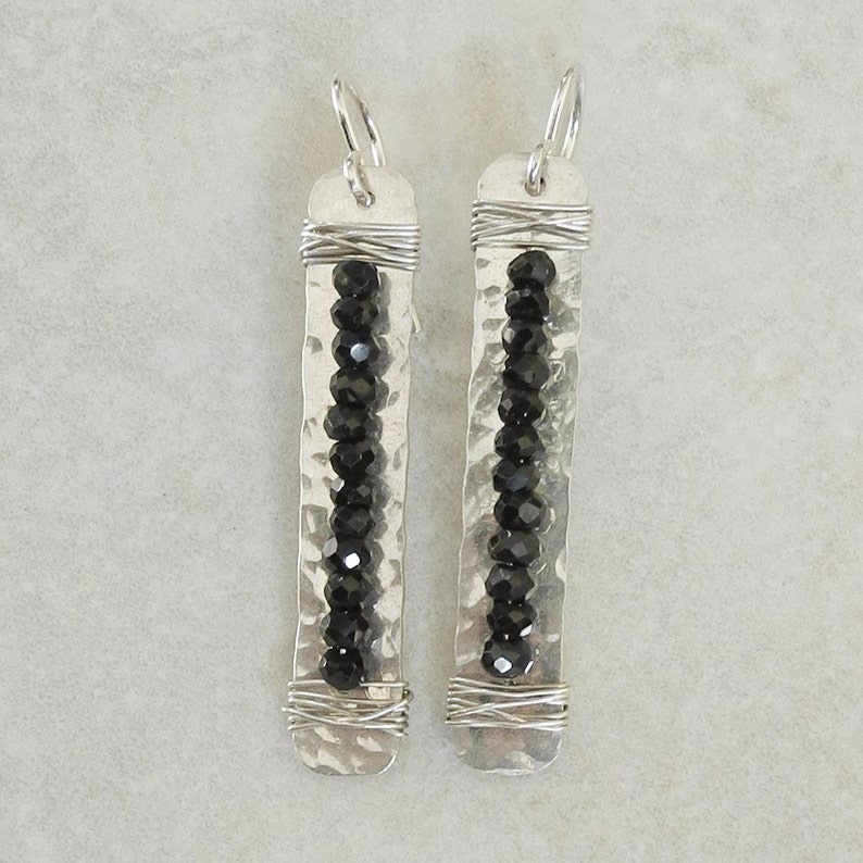 May include: A pair of silver earrings with black beads and hammered metal accents.