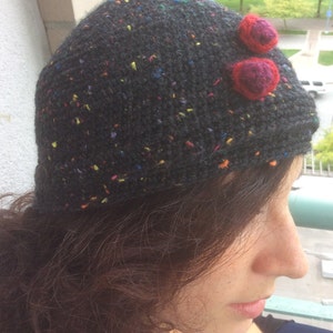 May include: A black beanie with colourful flecks and two red felt flower embellishments.