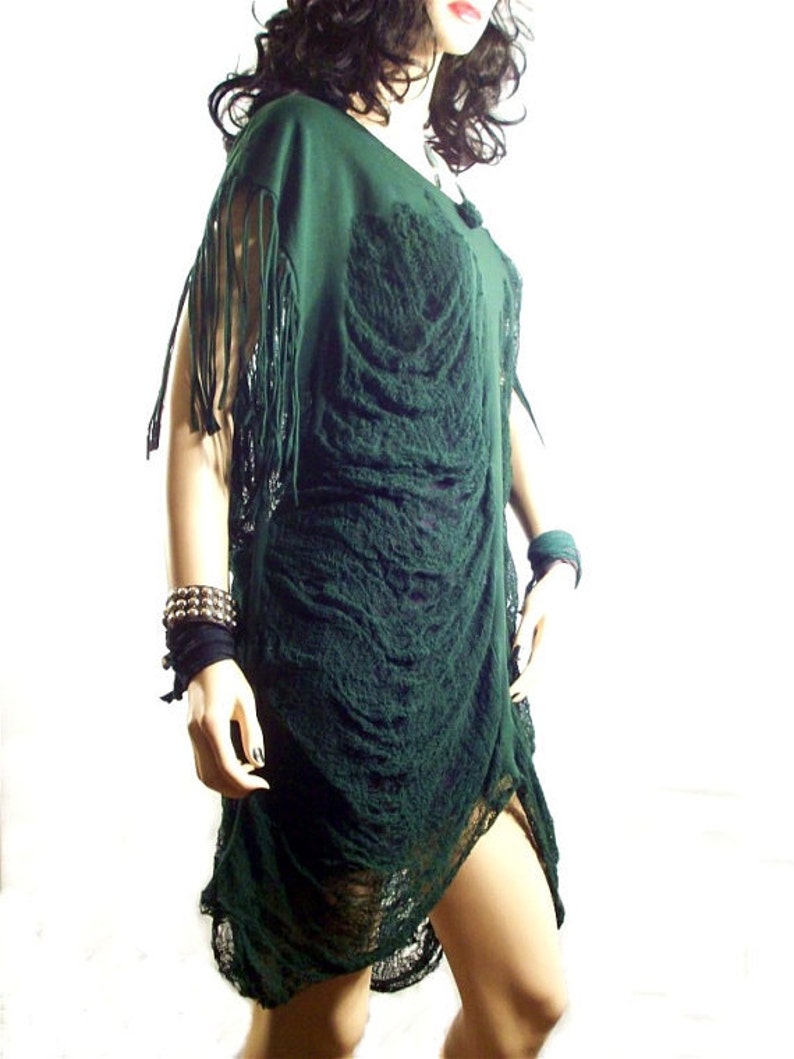 May include: A dark green, loose-fitting, fringed dress with a textured, almost crocheted, design. The dress has a scoop neckline and a flowing, asymmetrical hem.