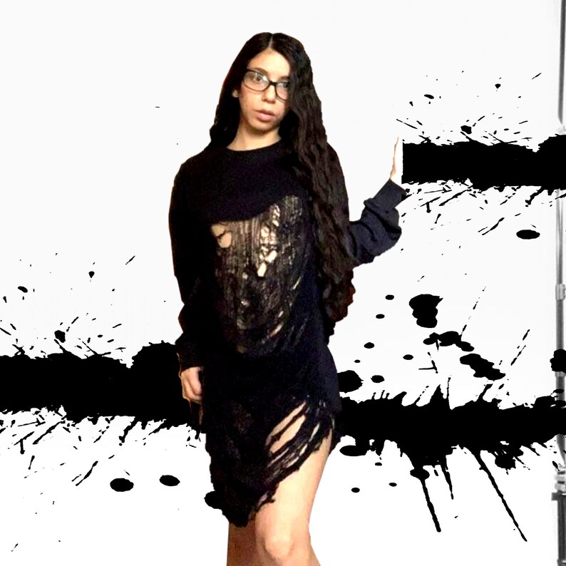 K&ouml;nnte beinhalten: Ein schwarzes Langarmshirt mit einem abgenutzten Design. Das Shirt hat mehrere Risse und L&ouml;cher, die einen Grunge-Look erzeugen.