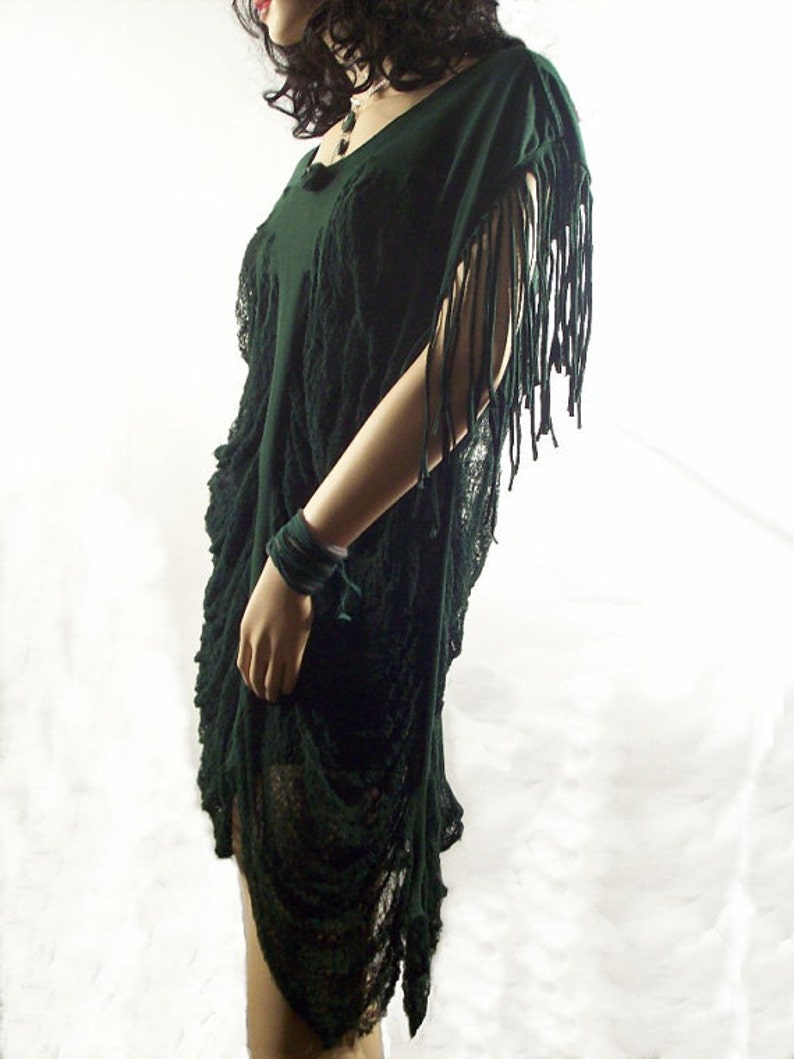 May include: A dark green, loose-fitting,  tunic-style dress with fringe detailing on the sleeves. The dress is made of a soft, flowing fabric and has a relaxed fit.