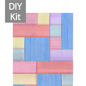 Op de afbeelding: Een patchworkdeken met vierkanten van roze, gele, blauwe en paarse stof. De stof heeft een subtiele glans en is met een decoratieve steek aan elkaar gestikt.