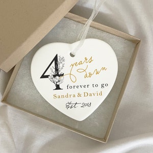 May include: White ceramic heart ornament with black floral design and gold lettering. The ornament reads "4 years down forever to go Sandra & David Est. 2018".