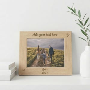 May include: A light-colored wooden picture frame with a family photo inside. The frame has the text "Add your text here" at the top and "Line 2" and "Line 3" at the bottom. Small heart shapes are etched into the frame.