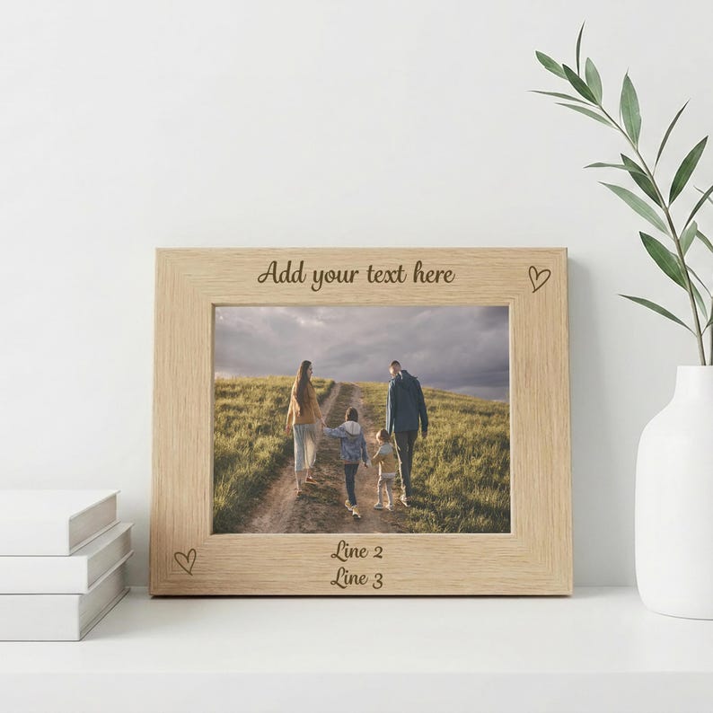 May include: A light-colored wooden picture frame with a family photo inside. The frame has the text "Add your text here" at the top and "Line 2" and "Line 3" at the bottom. Small heart shapes are etched into the frame.