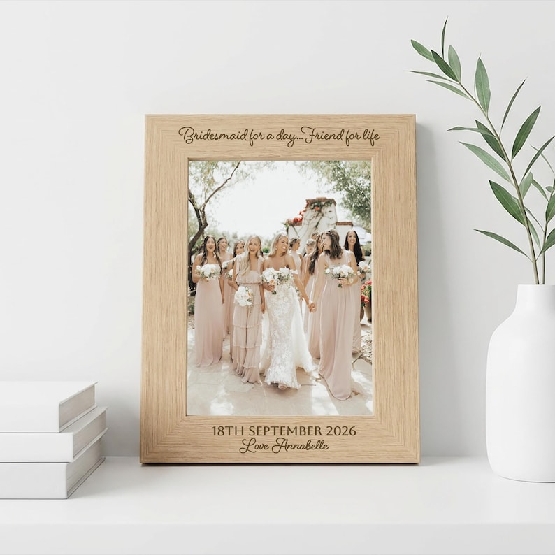 May include: A light wood picture frame containing a photograph of a wedding party. The top of the frame is engraved with "Bridesmaid for a day... Friend for life" and the bottom is engraved with "18TH SEPTEMBER 2026" and "Love Annabelle".