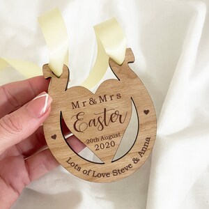 May include: Wooden horseshoe-shaped ornament with a cutout heart in the center. The ornament is personalized with the text "Mr & Mrs Easter", "20th August 2020", and "Lots of Love Steve & Anna".