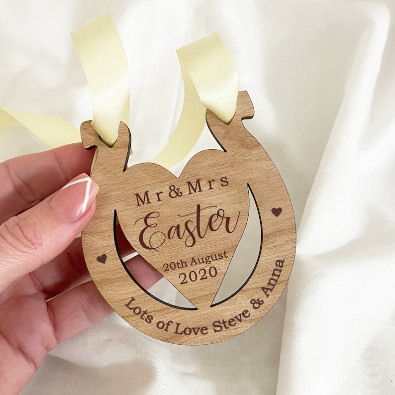 May include: Wooden horseshoe-shaped ornament with a cutout heart in the center. The ornament is personalized with the text "Mr & Mrs Easter", "20th August 2020", and "Lots of Love Steve & Anna".