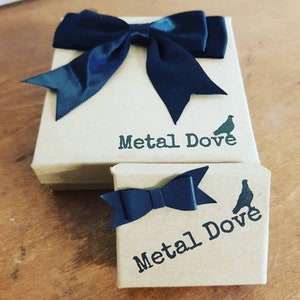 May include: Two brown gift boxes with black ribbon bows. The boxes are labeled "Metal Dove" and feature a small dove silhouette.