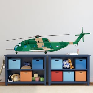 May include: A green and tan camouflage helicopter decal on a blue bookshelf with shelves filled with colourful storage bins and a skateboard leaning against the shelf.