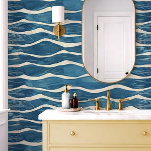 May include: A bathroom scene featuring a yellow vanity with gold hardware, a marble countertop, and a large oval mirror. The blue and white wave-patterned wallpaper complements the black and white diamond-patterned floor. Towels and baskets add texture.
