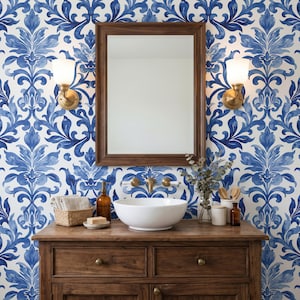 May include: A bathroom vanity featuring a wooden cabinet with a white ceramic vessel sink, a rectangular wooden mirror, and two wall-mounted brass sconces. The wall is covered in wallpaper with a repeating blue and white damask floral pattern.
