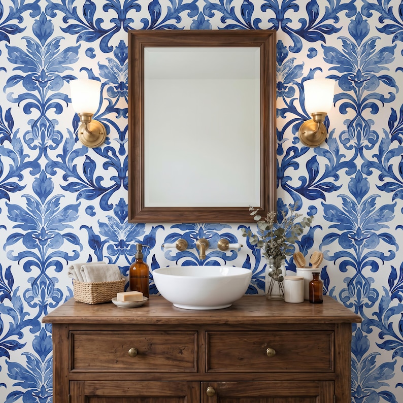 May include: A bathroom vanity featuring a wooden cabinet with a white ceramic vessel sink, a rectangular wooden mirror, and two wall-mounted brass sconces. The wall is covered in wallpaper with a repeating blue and white damask floral pattern.