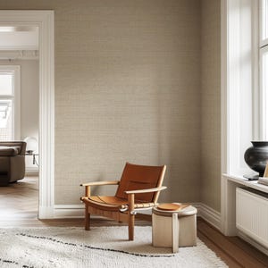 May include: A room with beige textured wallpaper, a wooden chair with a brown leather seat, and a small wooden side table. A white rug with a black geometric design is on the floor. A window with a black vase is on the right.
