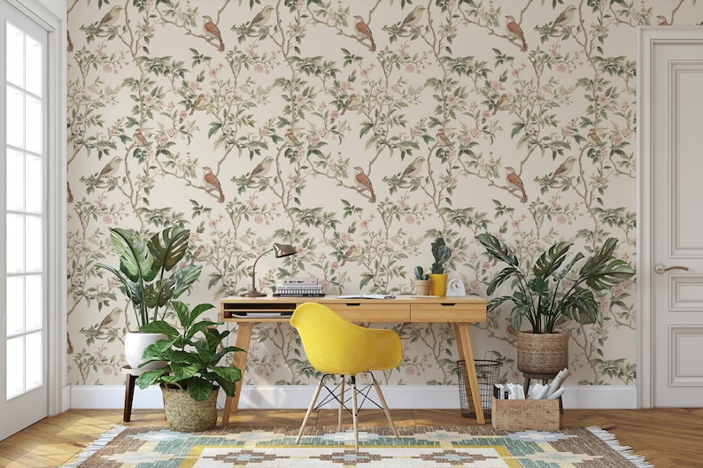 May include: A home office featuring a light wood desk and a yellow chair. The wall is adorned with wallpaper featuring a floral pattern and birds. Two potted plants add a touch of greenery to the space.