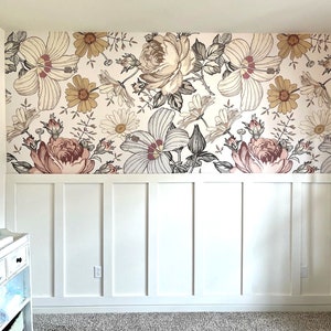 May include: A white wall with white wainscoting and a floral wallpaper featuring pink, brown, and white flowers.