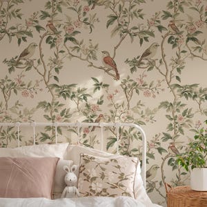 May include: A white metal bed frame with a white and pink bedding set. The headboard features wallpaper with a floral pattern and small birds. A stuffed bunny sits on the bed.
