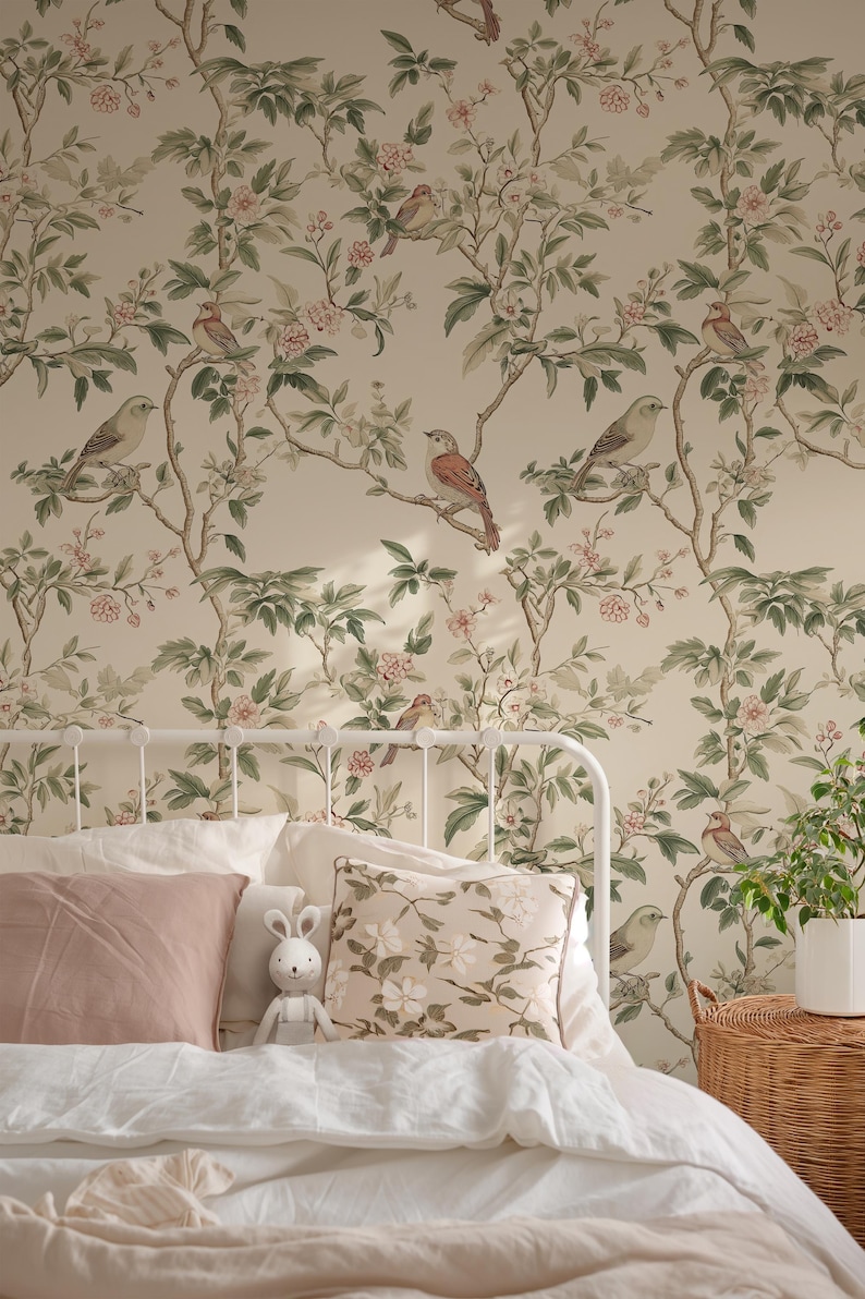 May include: A white metal bed frame with a white and pink bedding set. The headboard features wallpaper with a floral pattern and small birds. A stuffed bunny sits on the bed.