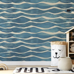 May include: A child's room with a blue and white wave-patterned wallpaper. A wooden house-shaped shelf holds toys. A white bunny sits on a small chair. A bear-faced storage bag and a woven basket are on the floor.