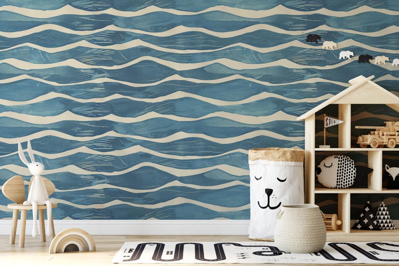 May include: A child's room with a blue and white wave-patterned wallpaper. A wooden house-shaped shelf holds toys. A white bunny sits on a small chair. A bear-faced storage bag and a woven basket are on the floor.