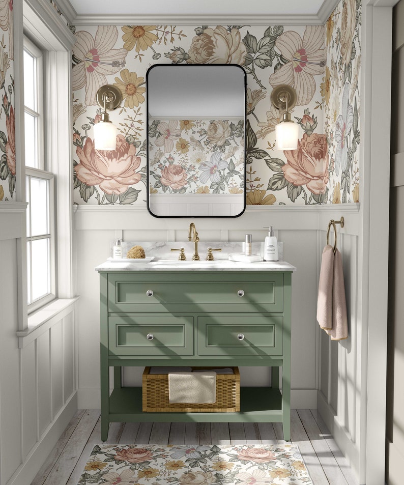 May include: A green bathroom vanity with a white marble countertop and a black framed mirror. The vanity has three drawers and a lower shelf. The walls are covered in floral wallpaper with a white background.
