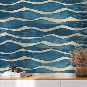 May include: A blue and cream-colored wallpaper with a wave pattern. The design features horizontal, undulating lines in varying shades of blue, with cream-colored wave crests. The wallpaper is displayed on a wooden surface with decorative items.