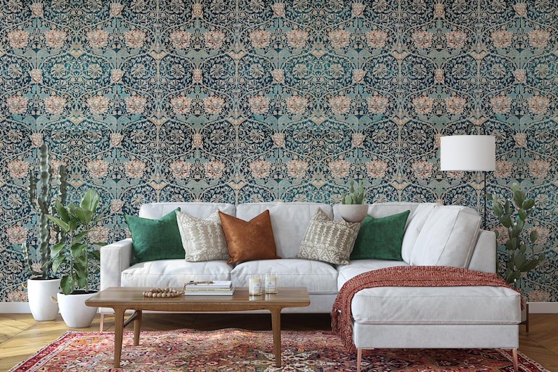 May include: A living room scene featuring a white sectional sofa with green and brown throw pillows, a wooden coffee table, and a patterned rug. The wall is covered in a teal and beige floral wallpaper. Potted plants and a lamp complete the decor.