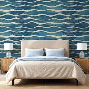 May include: A bedroom scene featuring a bed with a beige headboard, light blue pillows, and a beige comforter. The wall behind the bed is adorned with a blue and white wave pattern wallpaper. Wicker bedside tables with lamps complete the room's decor.