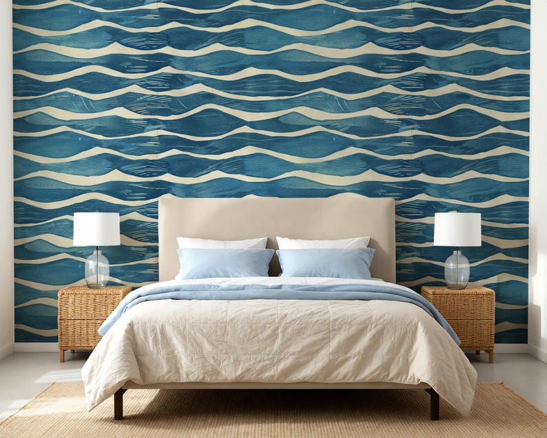 May include: A bedroom scene featuring a bed with a beige headboard, light blue pillows, and a beige comforter. The wall behind the bed is adorned with a blue and white wave pattern wallpaper. Wicker bedside tables with lamps complete the room's decor.