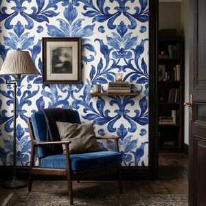 May include: Wallpaper featuring a repeating blue and white damask pattern on a wall. The design consists of symmetrical, stylized floral and leaf motifs in varying shades of blue against a cream background, creating a bold, decorative visual.