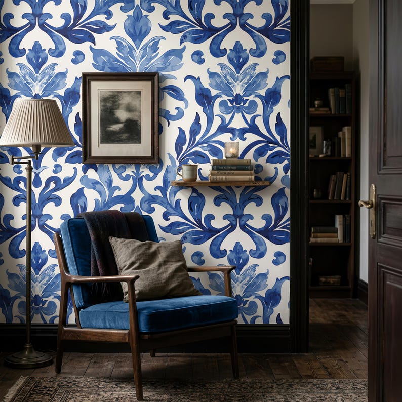 May include: Wallpaper featuring a repeating blue and white damask pattern on a wall. The design consists of symmetrical, stylized floral and leaf motifs in varying shades of blue against a cream background, creating a bold, decorative visual.