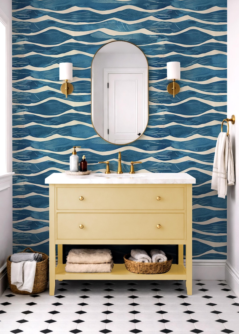 May include: A bathroom scene featuring a yellow vanity with gold hardware, a marble countertop, and a large oval mirror. The blue and white wave-patterned wallpaper complements the black and white diamond-patterned floor. Towels and baskets add texture.