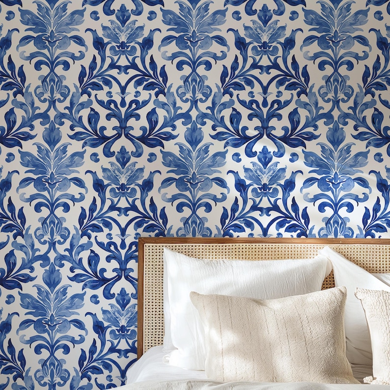 May include: Wallpaper featuring a repeating blue and white damask pattern with intricate floral and leaf motifs. The design consists of symmetrical, flowing shapes in various shades of blue against a solid white background, creating a continuous print.