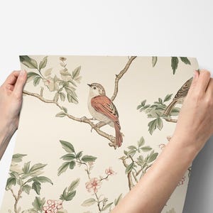 May include: A cream-coloured wallpaper with a repeating pattern of delicate pink flowers, green leaves, and brown birds. The birds are perched on branches and have a realistic, detailed design.