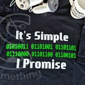 May include: A black t-shirt with white text that reads "It's Simple" and a line of binary code in green. The text "I Promise" is below the code. The words "Something" are at the bottom of the shirt.