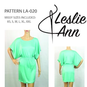 May include: A green, short-sleeved dress with a gathered waist and a round neckline. The dress is shown on two mannequins, one from the front and one from the back. The pattern is called "LA-020" and is available in sizes XS, S, M, L, XL, and XXL. The text "Leslie Ann" is also visible on the image.
