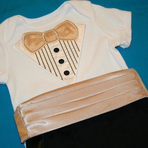 May include: A white bodysuit with a gold bow tie and a gold satin sash. The sash is pleated and has a smooth texture.