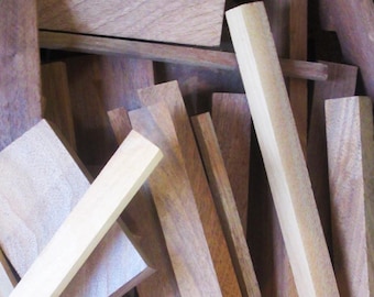 May include: A collection of various wooden planks and blocks in shades of brown and tan. The pieces vary in size and shape, with some appearing rectangular and others more square. The wood grain is visible, suggesting a natural material.