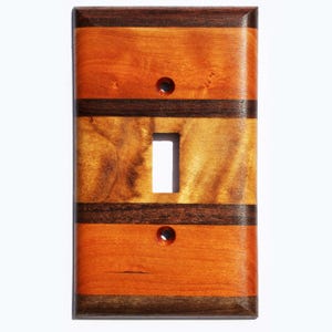 May include: A wooden light switch cover with a striped design. The cover is made of cherry and walnut wood and has a natural finish.